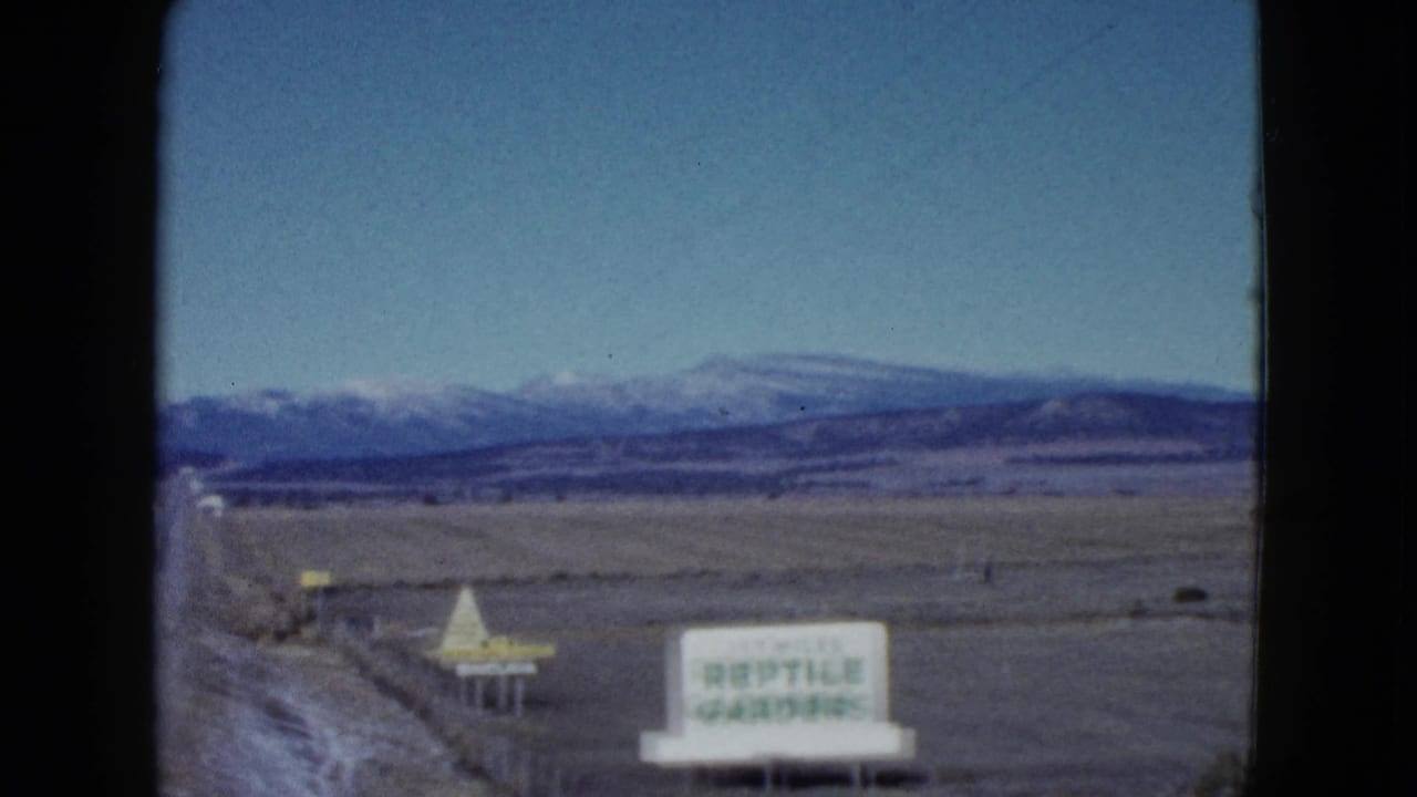 Roadside Reptile Gardens sign beside an open plain and distant mountains.