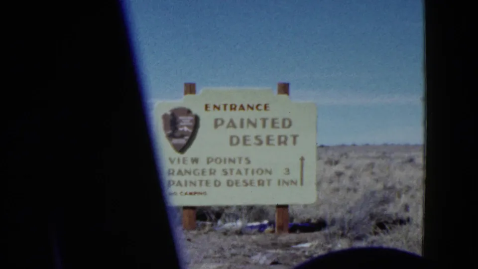 1950s 8mm frame of a Painted Desert entrance sign listing viewpoints, Ranger Station 3, and Painted Desert Inn.