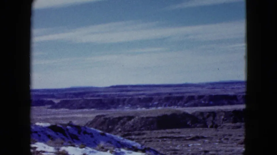 1958 8mm home-movie view of arid desert ridges and flats under a blue sky, likely part of the Painted Desert travel sequence.