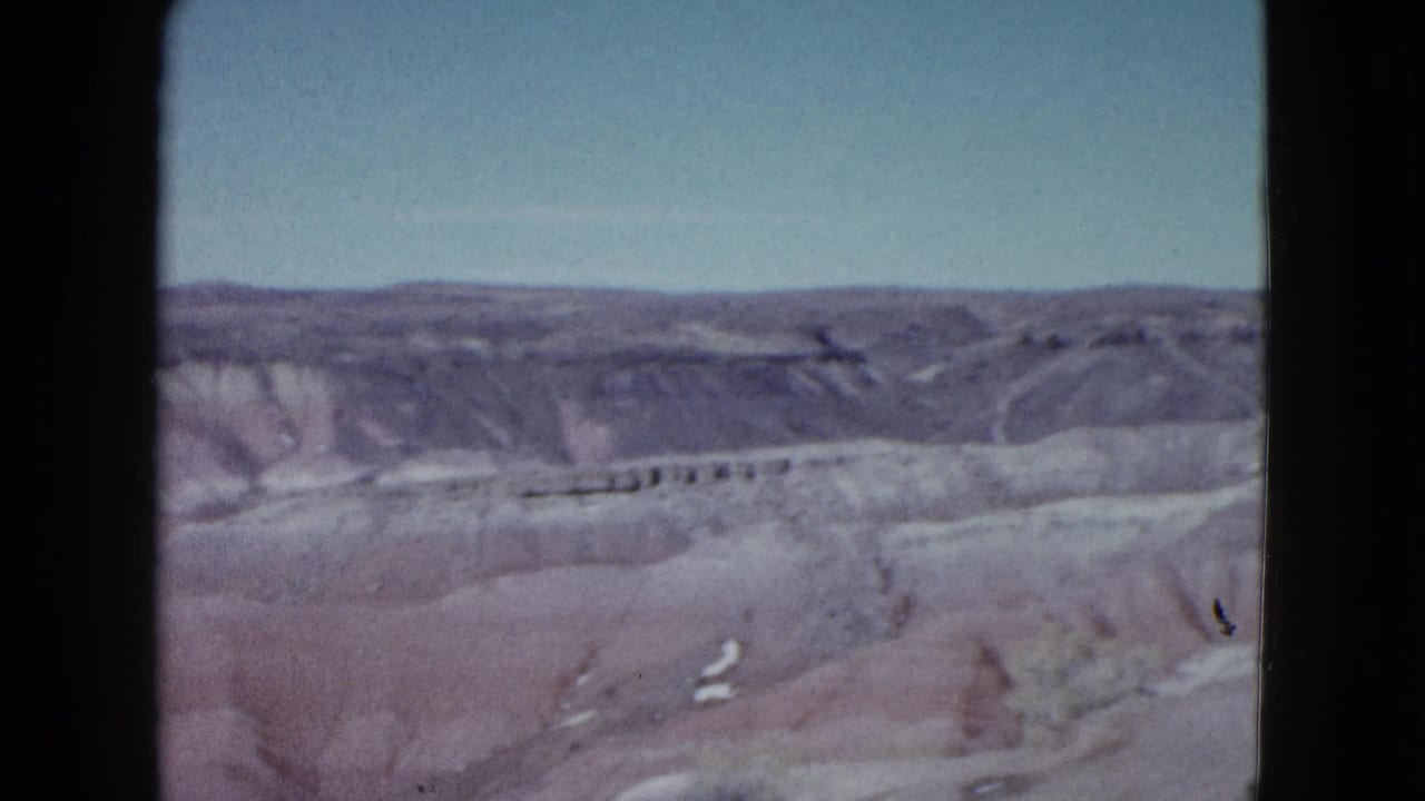 1958 Las Vegas-area 8mm frame showing pale desert terrain, distant ridges, and open sky from a roadside viewpoint.