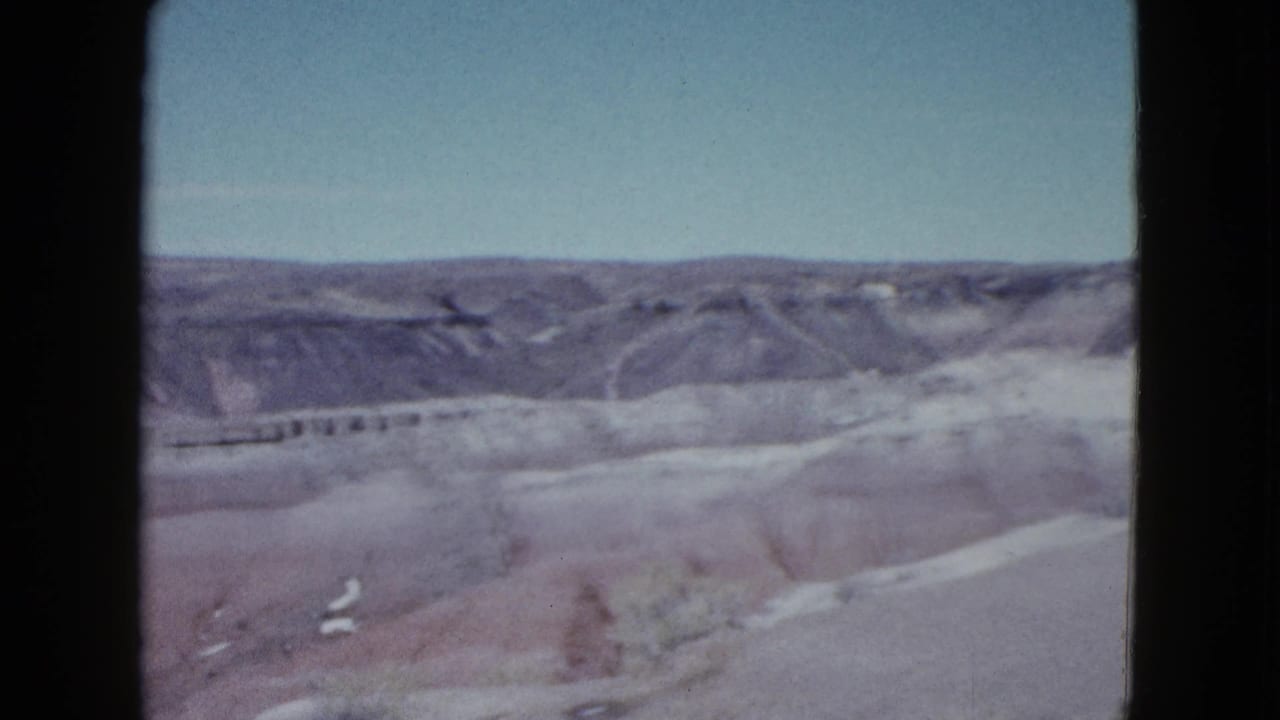 Las Vegas-area desert terrain appears in a soft 1958 home-movie frame with layered ridges and open sky.