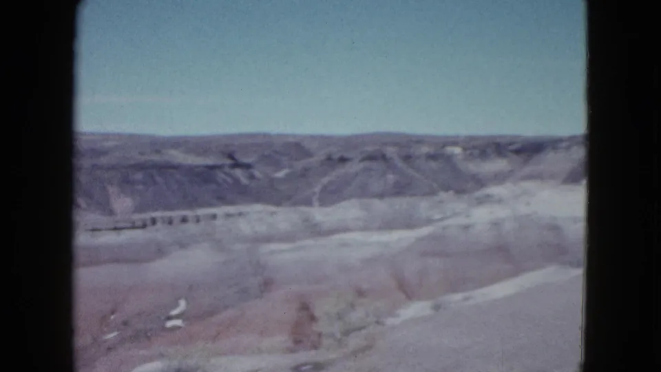 Las Vegas-area desert terrain appears in a soft 1958 home-movie frame with layered ridges and open sky.