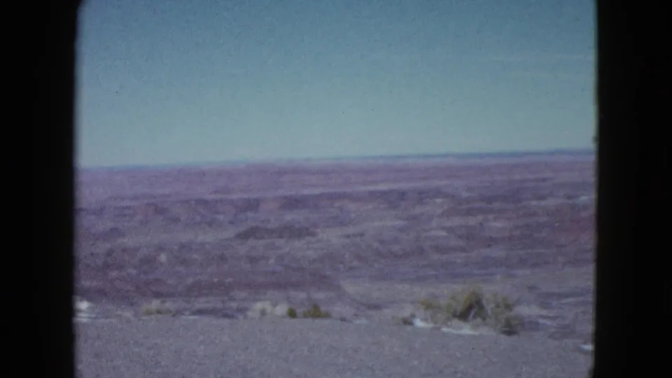 The camera looks across dry Nevada desert terrain near Las Vegas, showing open valley land, low ridges, and faded 8mm color.