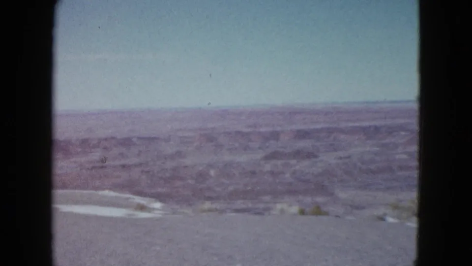 A Las Vegas-area desert panorama shows low ridges, open dry ground, and a pale wash or road through the distant landscape.
