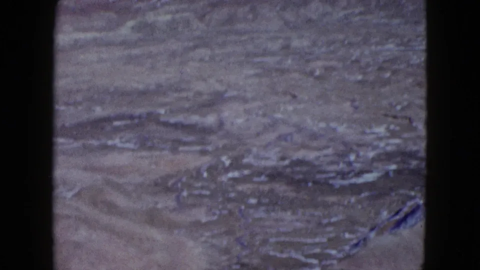 1958 Las Vegas-area desert basin with rocky ridges, pale washes, and a dark vertical edge from the window or film frame.