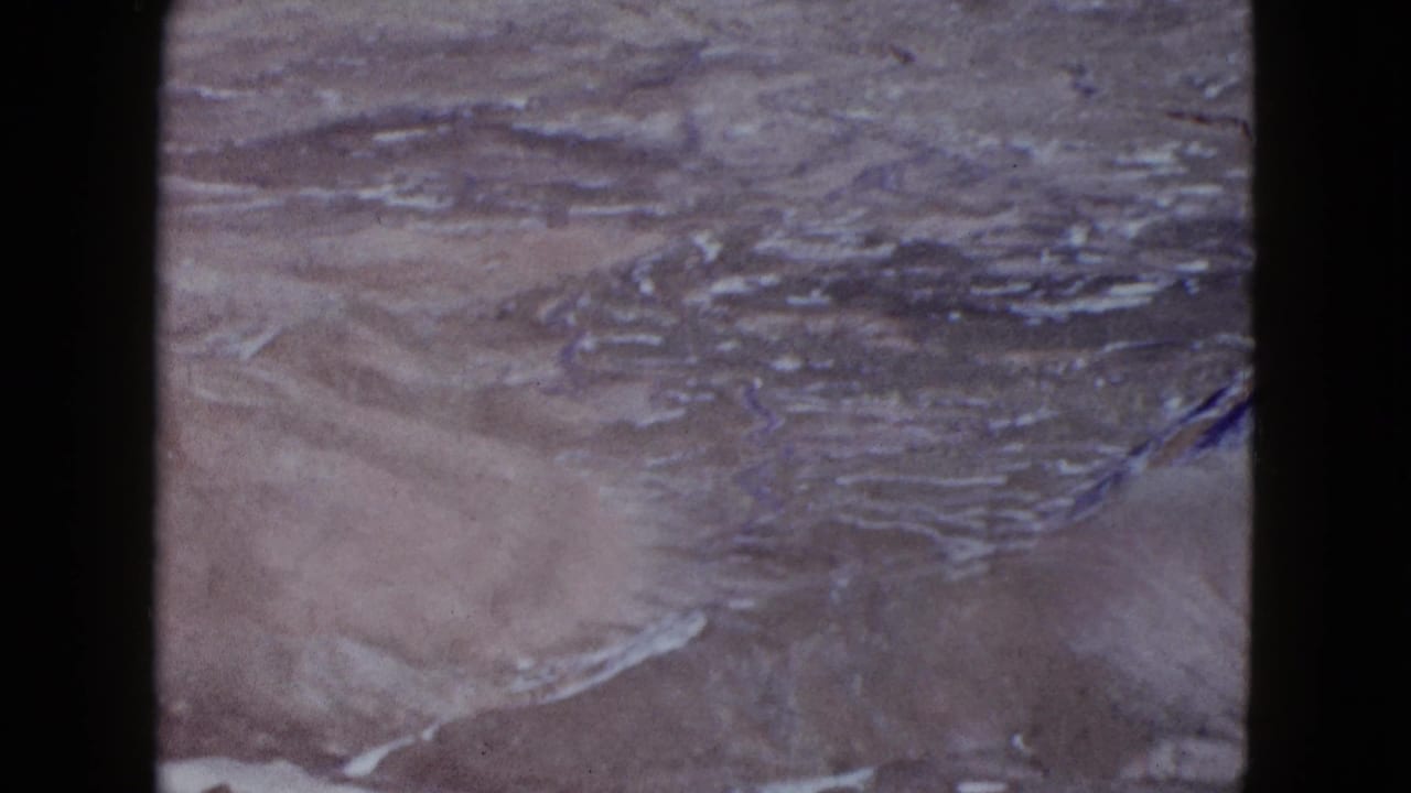 Aerial view over dry desert ridges and pale washes.