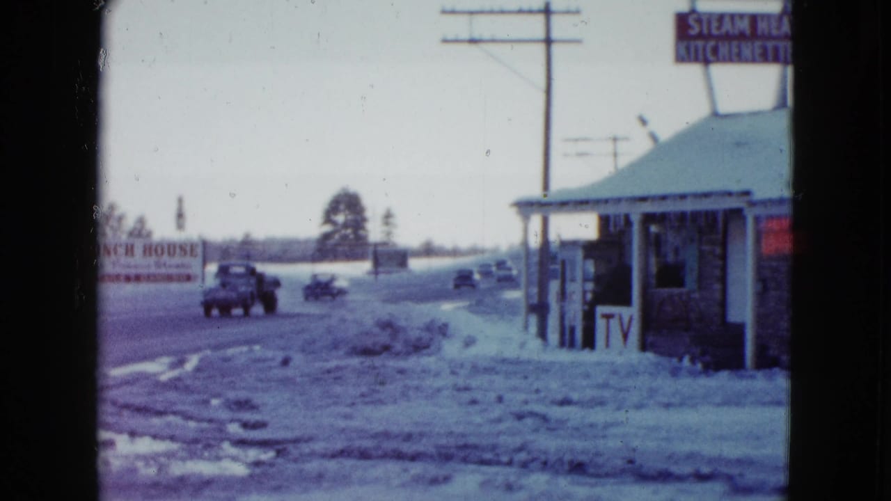 1958 Las Vegas roadside view with snow along the shoulder, mid-century vehicles, utility poles, and a small building with visible signage.