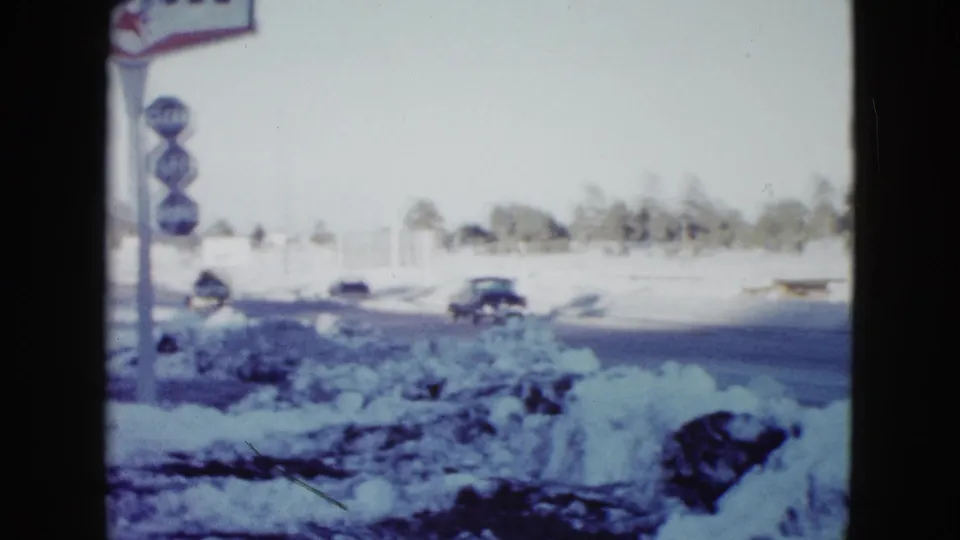 1958 Las Vegas snowy roadside viewed from inside a vehicle, with classic cars and a partially visible Mobil station sign.