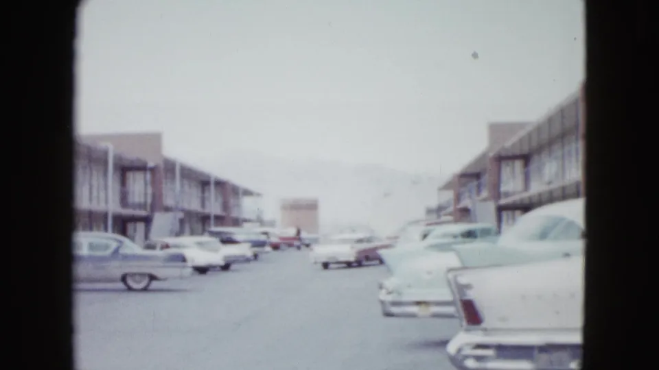 Las Vegas motel exterior with multiple 1950s automobiles parked along two-story lodging buildings.