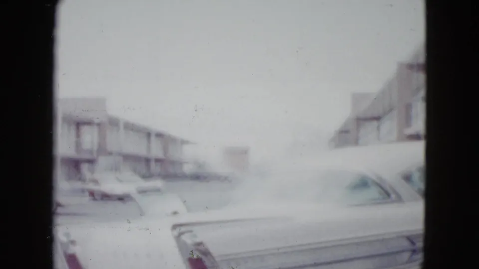 1958 Las Vegas home-movie frame showing a mid-century motel area with a classic car partly visible in the foreground.