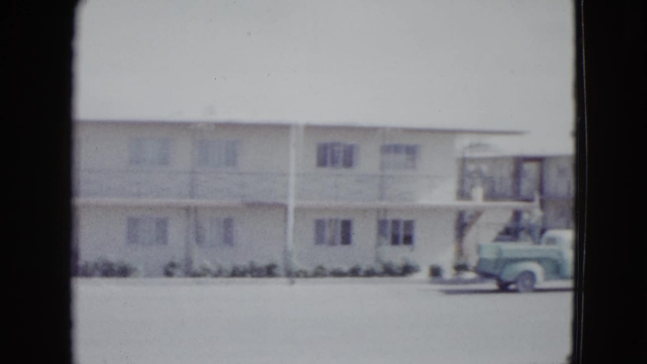 1958 Las Vegas motel exterior with a staircase, exterior corridor, and light green vintage pickup truck at the curb.