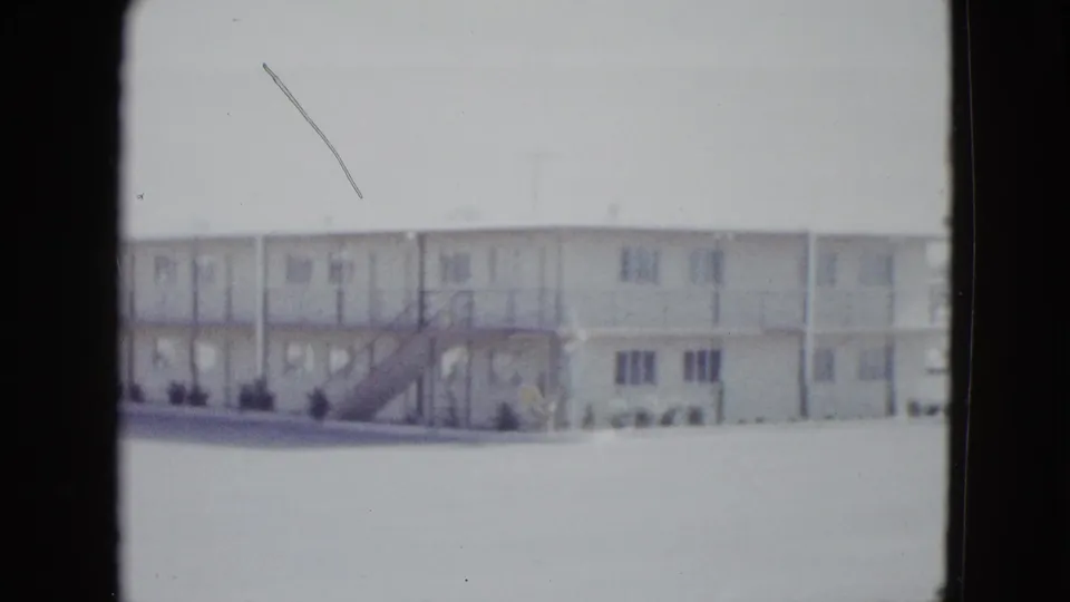 1958 Las Vegas frame of a low-rise white motel building, exterior stairway, repeated rooms, and sparse landscaping.