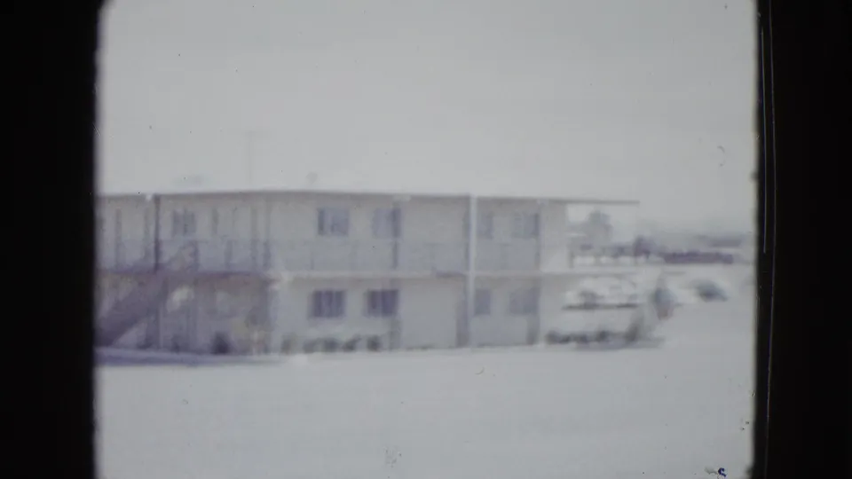 1958 Las Vegas home-movie view of the motel exterior, cropped toward the right side with parked vehicles near the lot edge.
