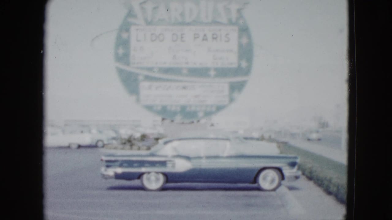 Dark car beside the curb with the Stardust sign filling the background.