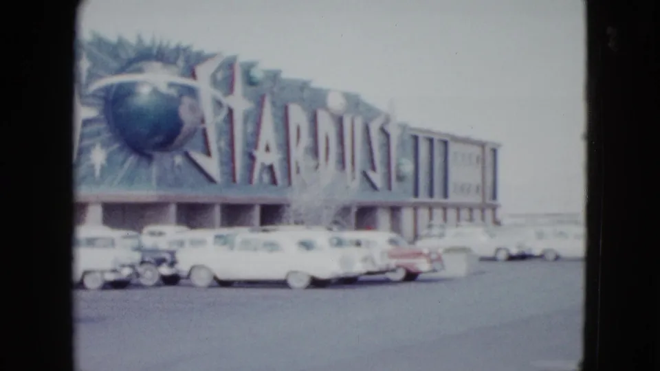 The Stardust Hotel facade in Las Vegas, with its globe and starburst sign above a row of 1950s cars.