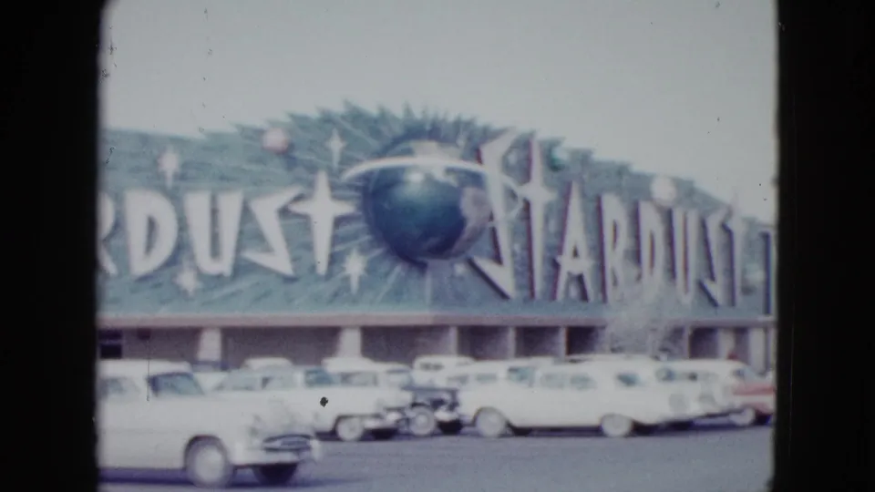End frame of the 1958 Las Vegas Stardust Hotel exterior, showing the sign, facade, and cars in the foreground.