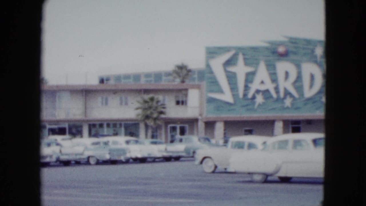 Stardust Hotel sign above a parking lot filled with vintage cars.