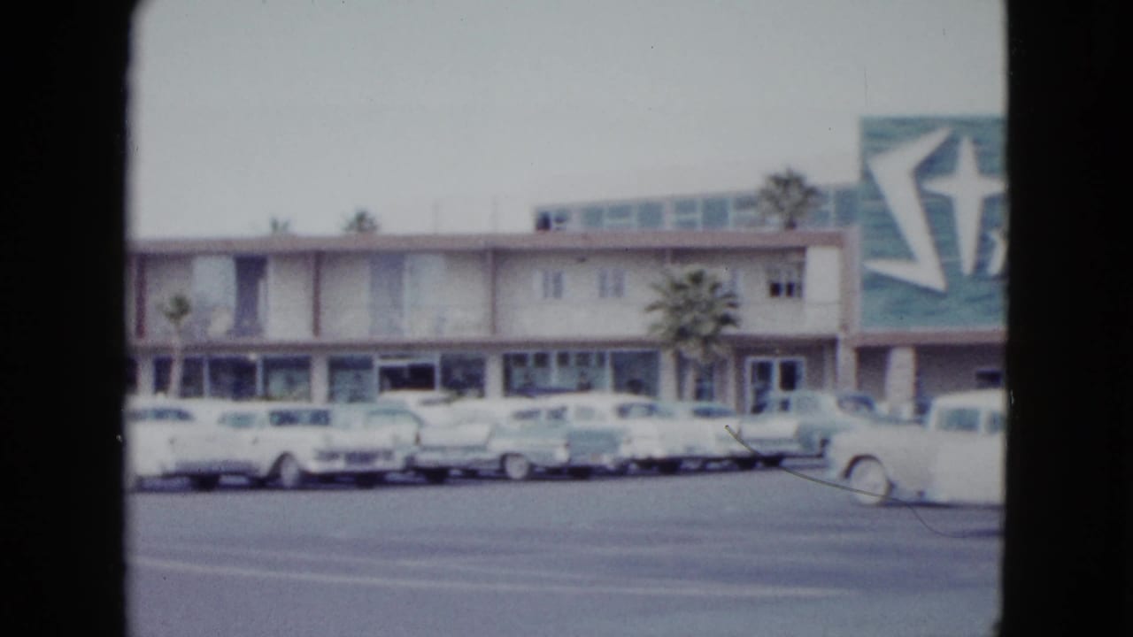 The camera view shifts along the Stardust Hotel frontage, showing parked cars and partial resort signage in Las Vegas.