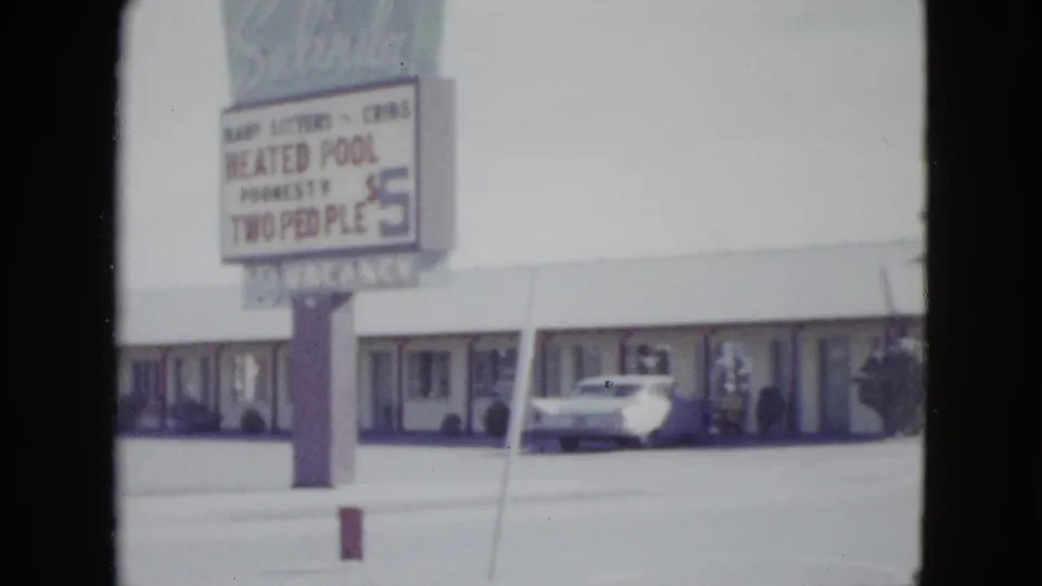 The Salinda Motel sign and single-story frontage appear in a soft 1958 Las Vegas 8mm frame with a light sedan near the rooms.