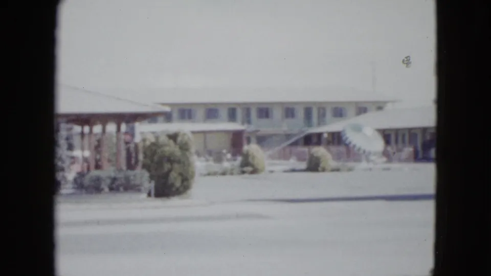 1958 Las Vegas home-movie view of a low motel building with striped awnings, landscaping, and street foreground.