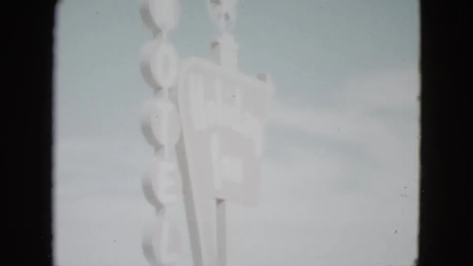 1958 Las Vegas home-movie frame showing the upper portion of a tall motel sign with vertical HOTEL letters.