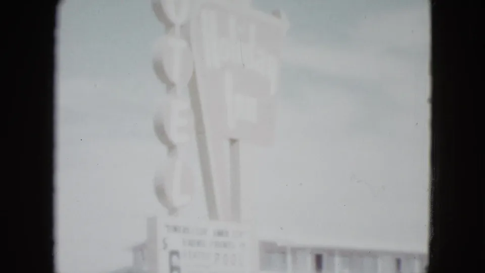 1958 Las Vegas frame with the Holiday Inn motel sign, partial rate board, and a low two-story building below.