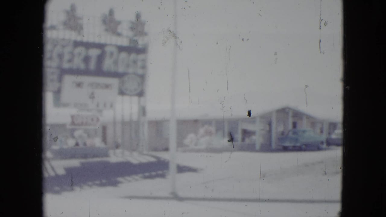 Desert Rose Motel sign beside a low roadside motel and parked car.