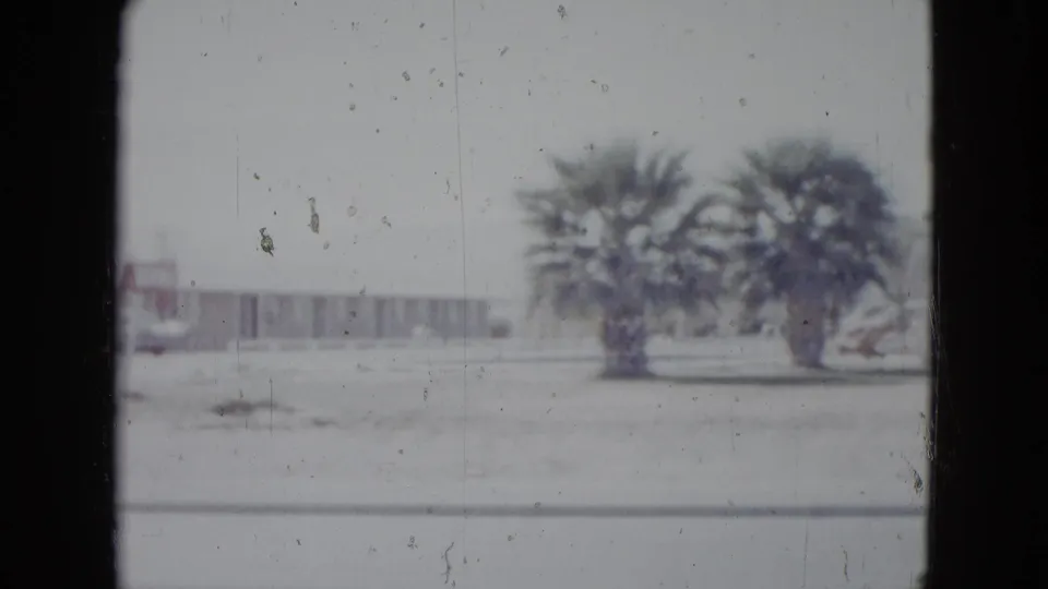 Las Vegas motel grounds with palm trees, low roadside buildings, open foreground, and faded home-movie exposure from 1958.