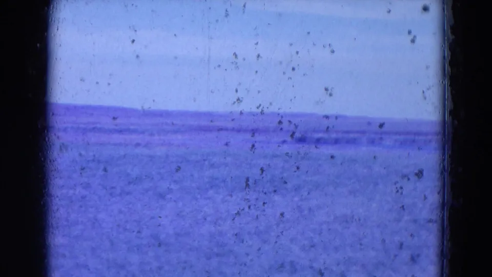 1958 8mm home-movie frame from metadata-listed Omaha, Nebraska, showing a distant purple-blue horizon and open terrain or water.