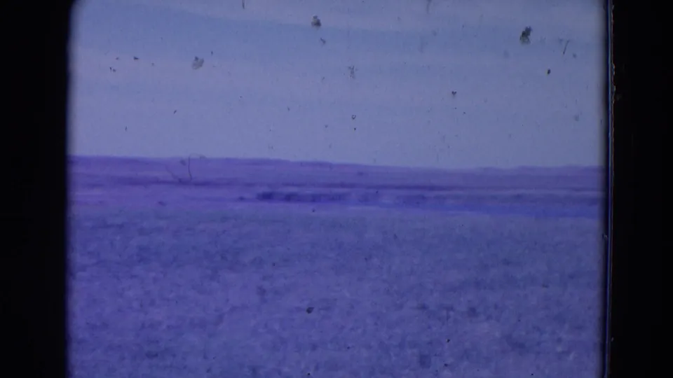 1958 8mm frame associated with Omaha, Nebraska, showing a washed purple-blue open view and faint distant land along the horizon.