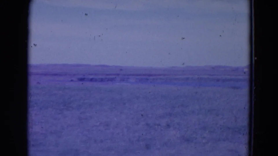 Metadata-supported 1958 Omaha home-movie frame showing a quiet open landscape or water surface with a low horizon and aged-film tint.