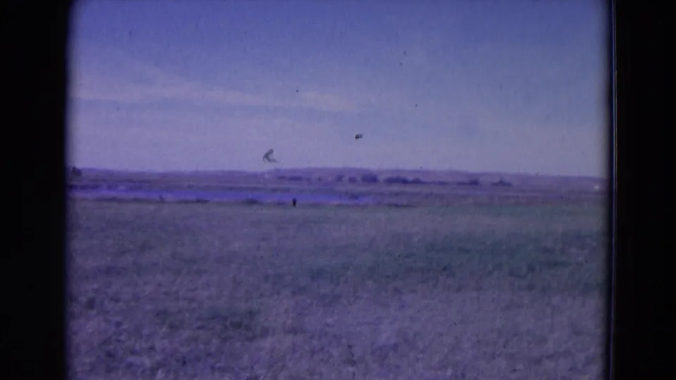 Wide 1958 home-movie view of an open landscape near Omaha, with grass, pale sky, and distant horizon features.