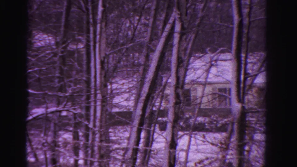 1958 Ontario 8mm frame showing snow-covered woods with leafless trees and a small house in the distance.