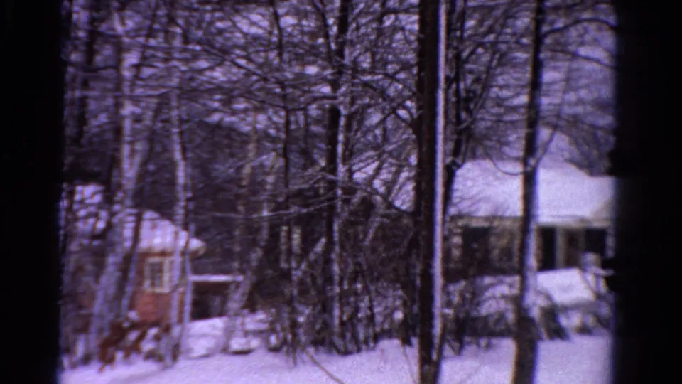 1958 Ontario winter frame with snow-covered houses, bare trees, a small red structure, and quiet residential yards.