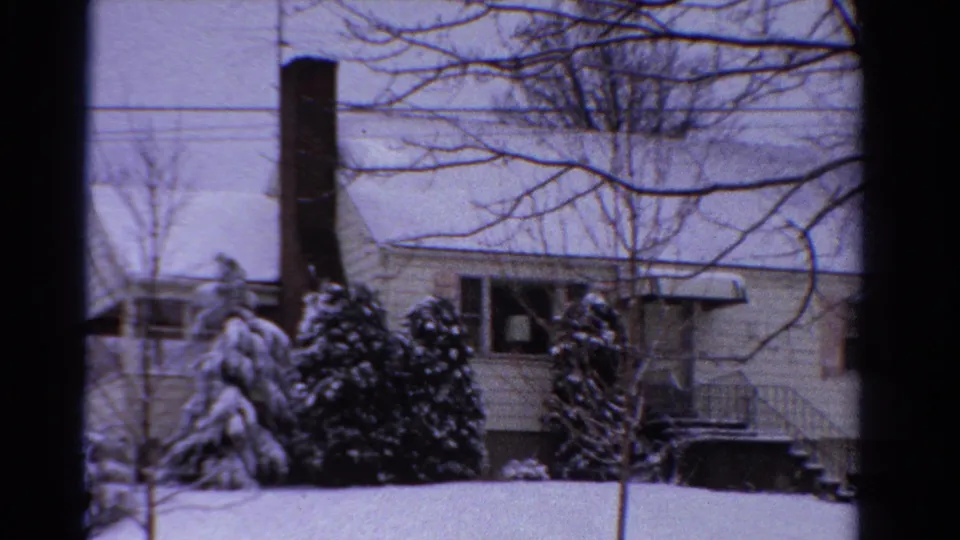 The clip ends on a wide 8mm view of a snowy Ontario house exterior with chimney, shrubs, bare branches, and a white yard.