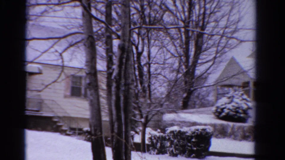 1958 Ontario frame with the edge of a snowy house, bare trees, shrubs, and a neighboring peaked roof partly visible.