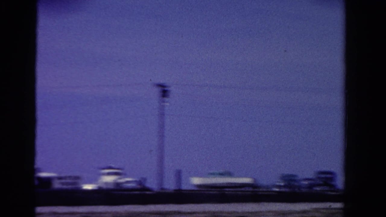 1958 Ontario frame showing a utility pole and overhead wires above distant low buildings in blue-shifted 8mm color.