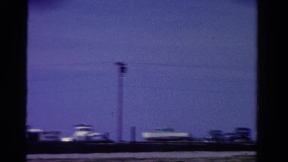 1958 Ontario frame showing a utility pole and overhead wires above distant low buildings in blue-shifted 8mm color.