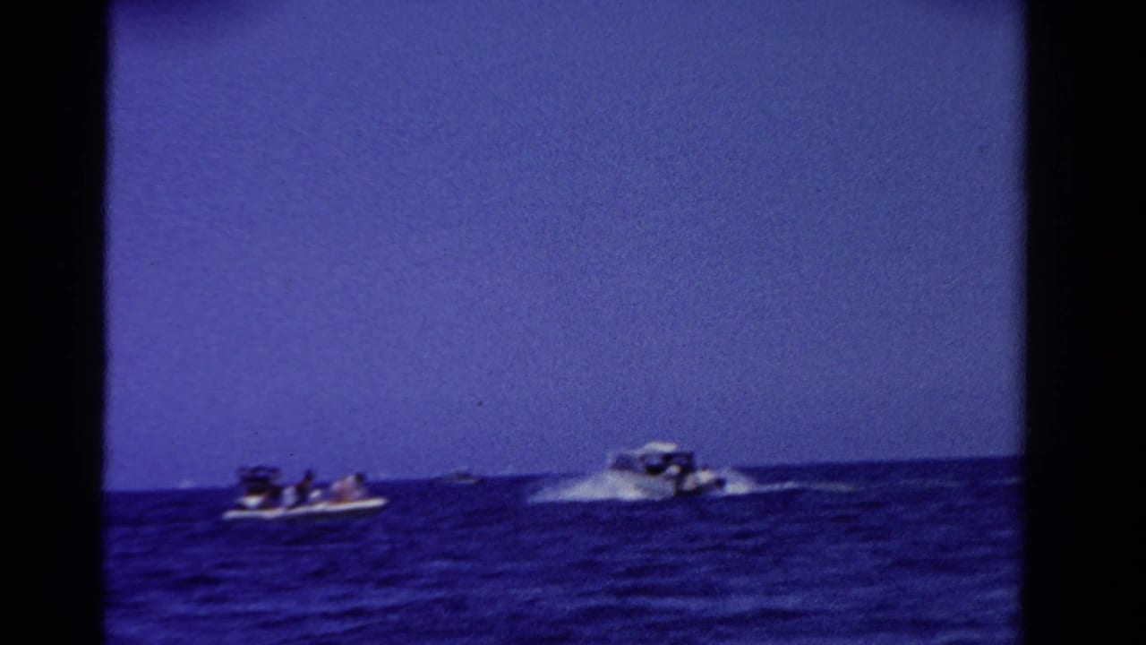Distant boats on Ontario water in 1958, with passengers visible in one craft and a speedboat throwing spray nearby.