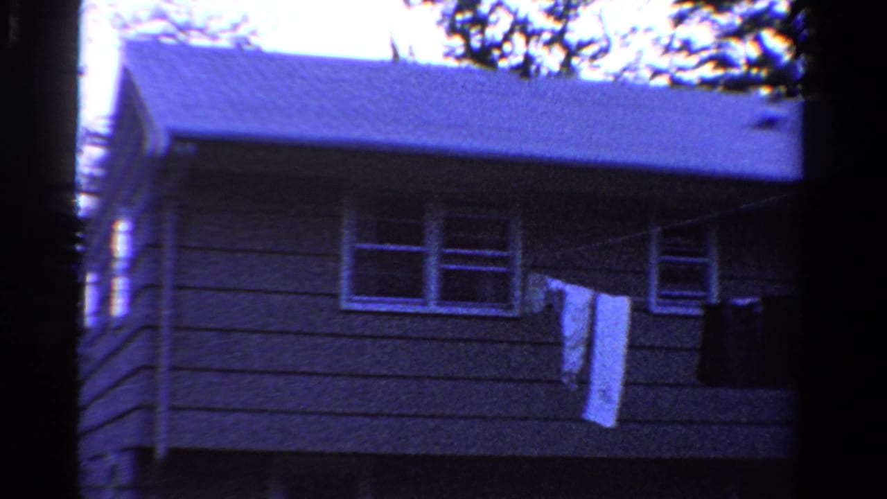 Gray house exterior with pale roof, windows, and laundry hanging on a clothesline.