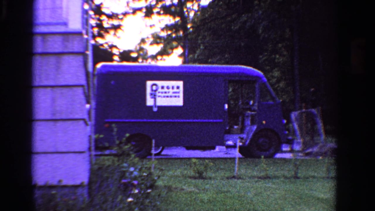 1958 Ontario yard scene with a blue delivery van carrying a visible company logo near the side of a house.