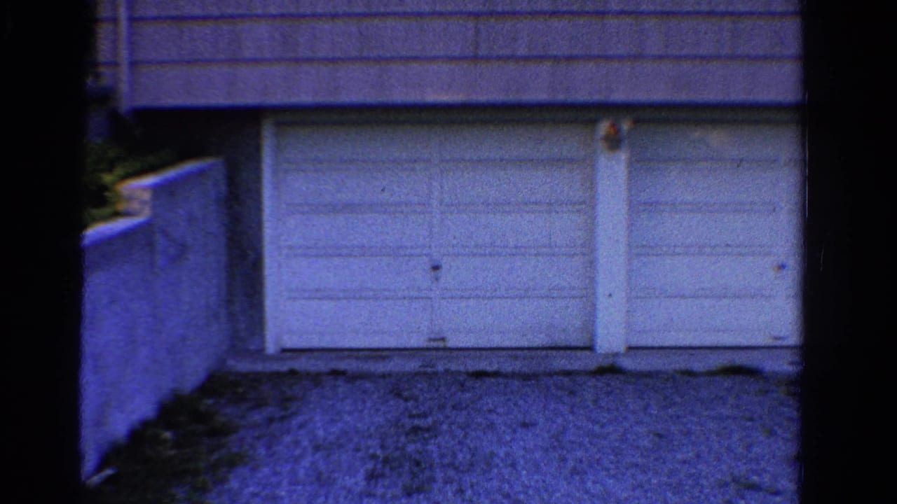 White double garage doors beside a low concrete wall.