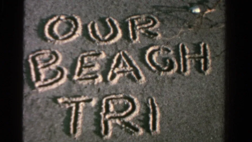 Close view of OUR BEACH TRIP written in sand in 1958 Ontario home-movie footage.