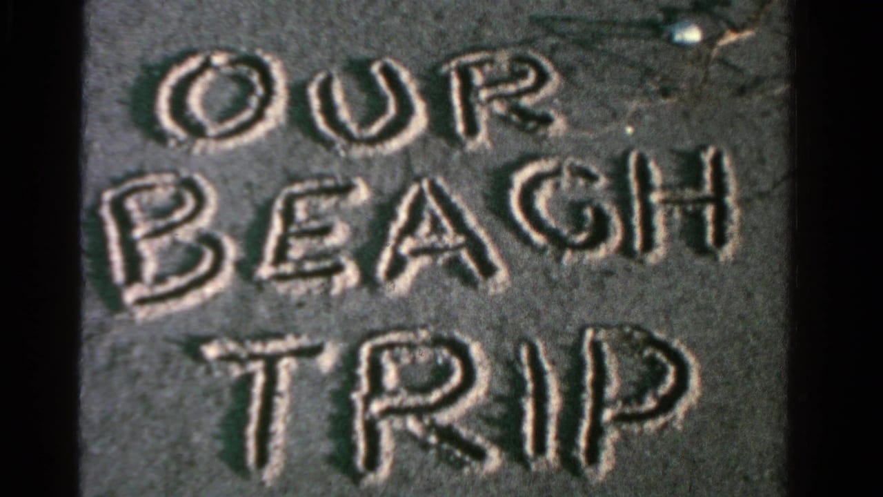 The sand title OUR BEACH TRIP remains in close-up, showing soft 8mm texture and uneven beach surface.