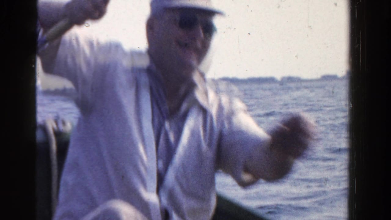 In 1958 Ontario home-movie footage, a man in a light shirt and cap fishes from a small boat on a calm lake.