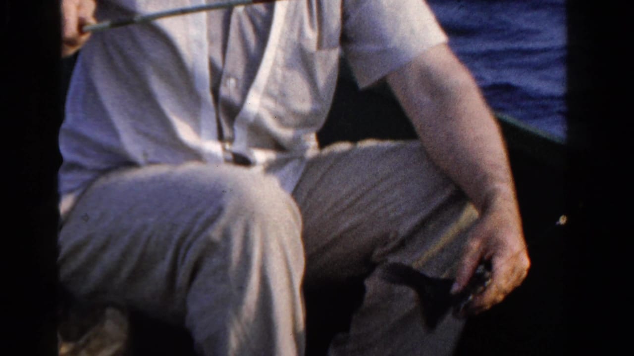 In 1958 Ontario home-movie footage, a man in light clothing sits in a small boat with fishing gear visible near open water.