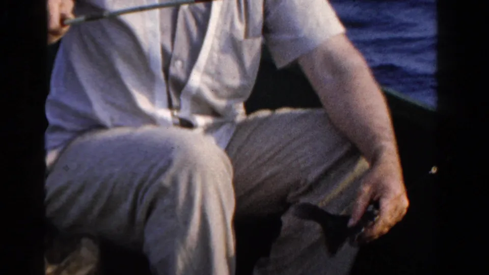 In 1958 Ontario home-movie footage, a man in light clothing sits in a small boat with fishing gear visible near open water.