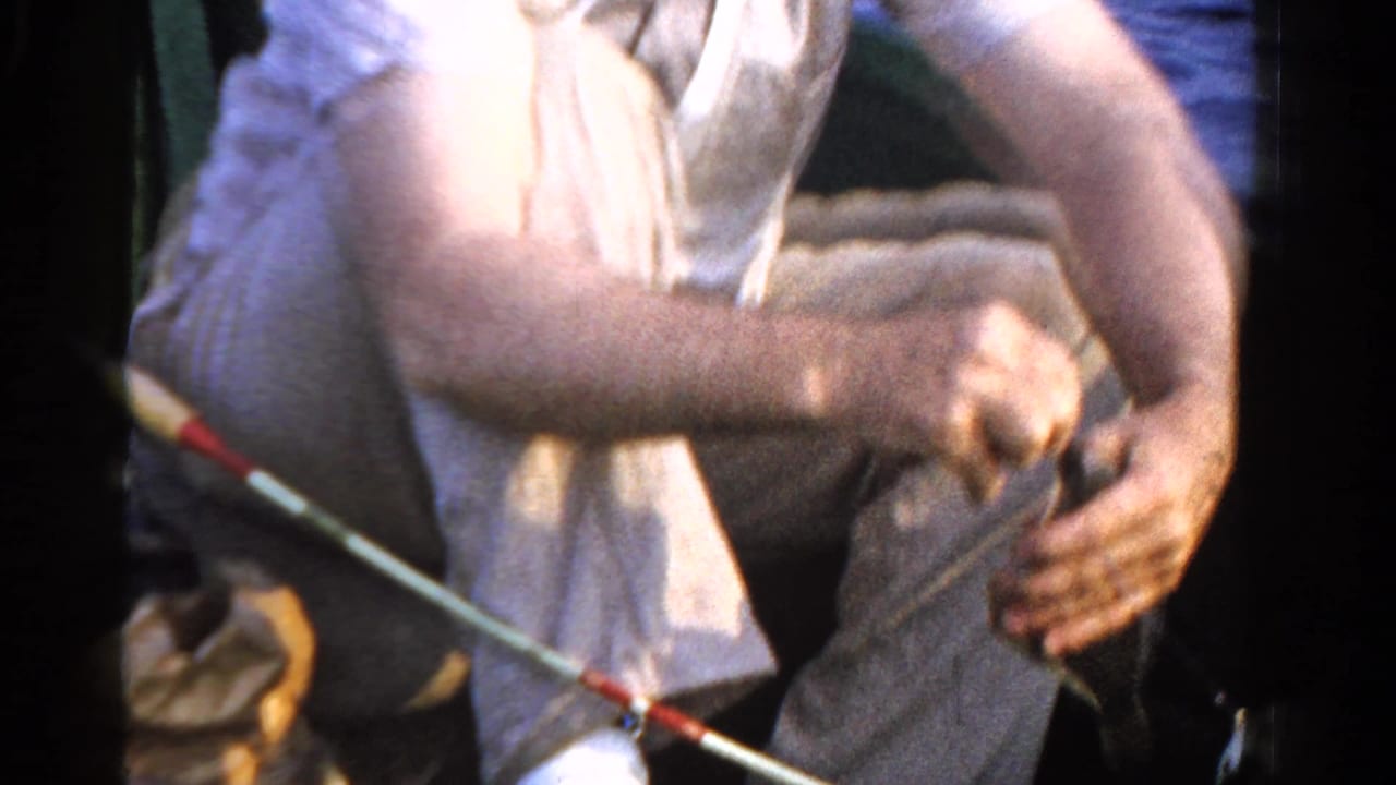 1958 Ontario fishing footage frame with the angler leaning forward while working the rod and line in a small boat.