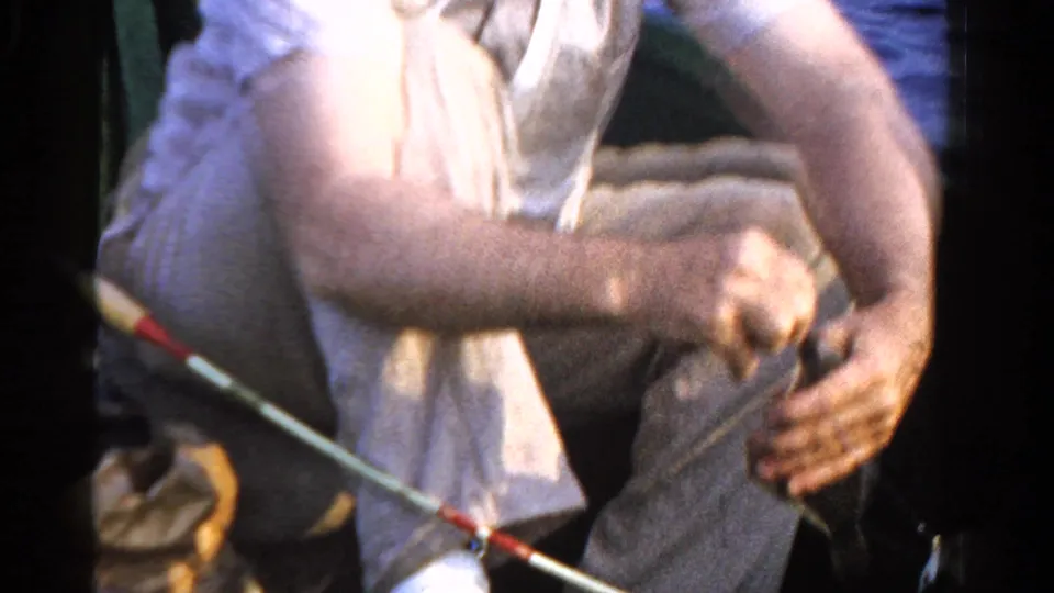1958 Ontario fishing footage frame with the angler leaning forward while working the rod and line in a small boat.