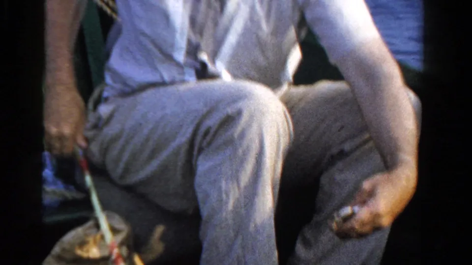 In 1958 Ontario home-movie footage, a seated man in light clothing handles fishing line inside a small boat.
